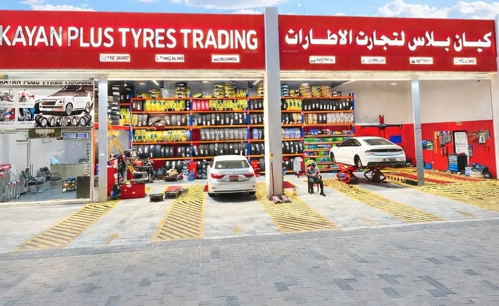 محل اطارات في مدينة شخبوط بأبوظبي: رفوف مليانة اطارات وسيارة في ورشة الخدمة